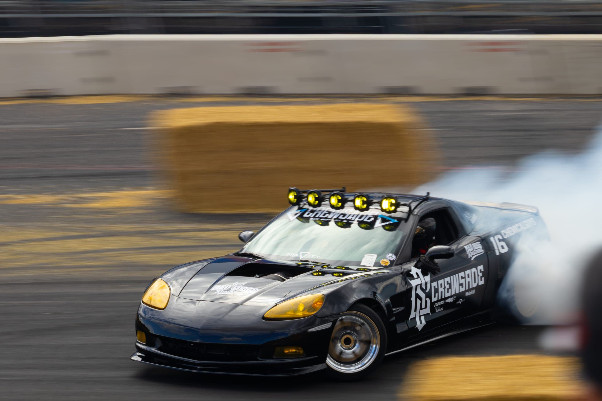 A dark liveried drift car front-on, lamp pod lit, Gravity 2026