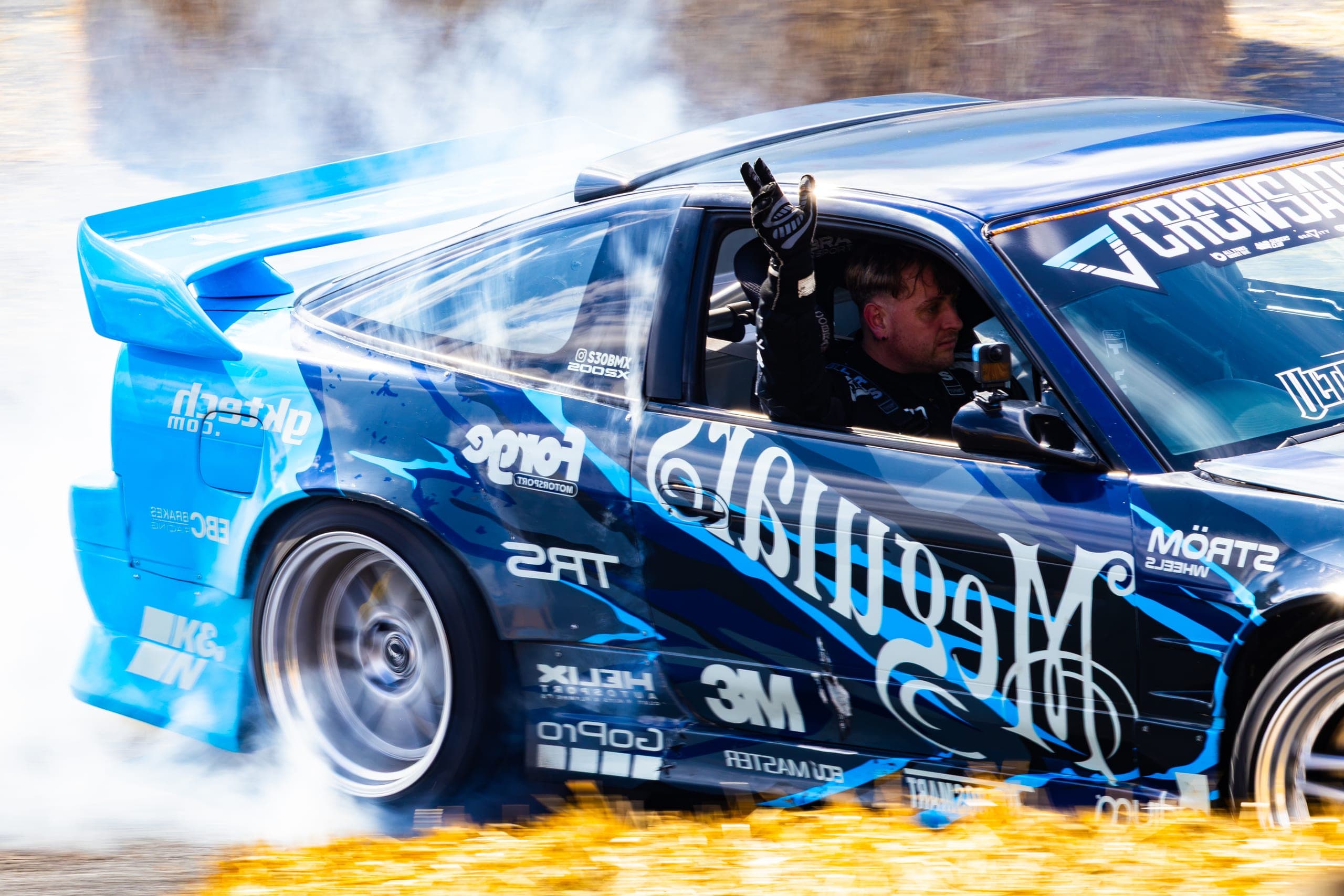 A driver with an arm out of the window mid-drift, Gravity 2026