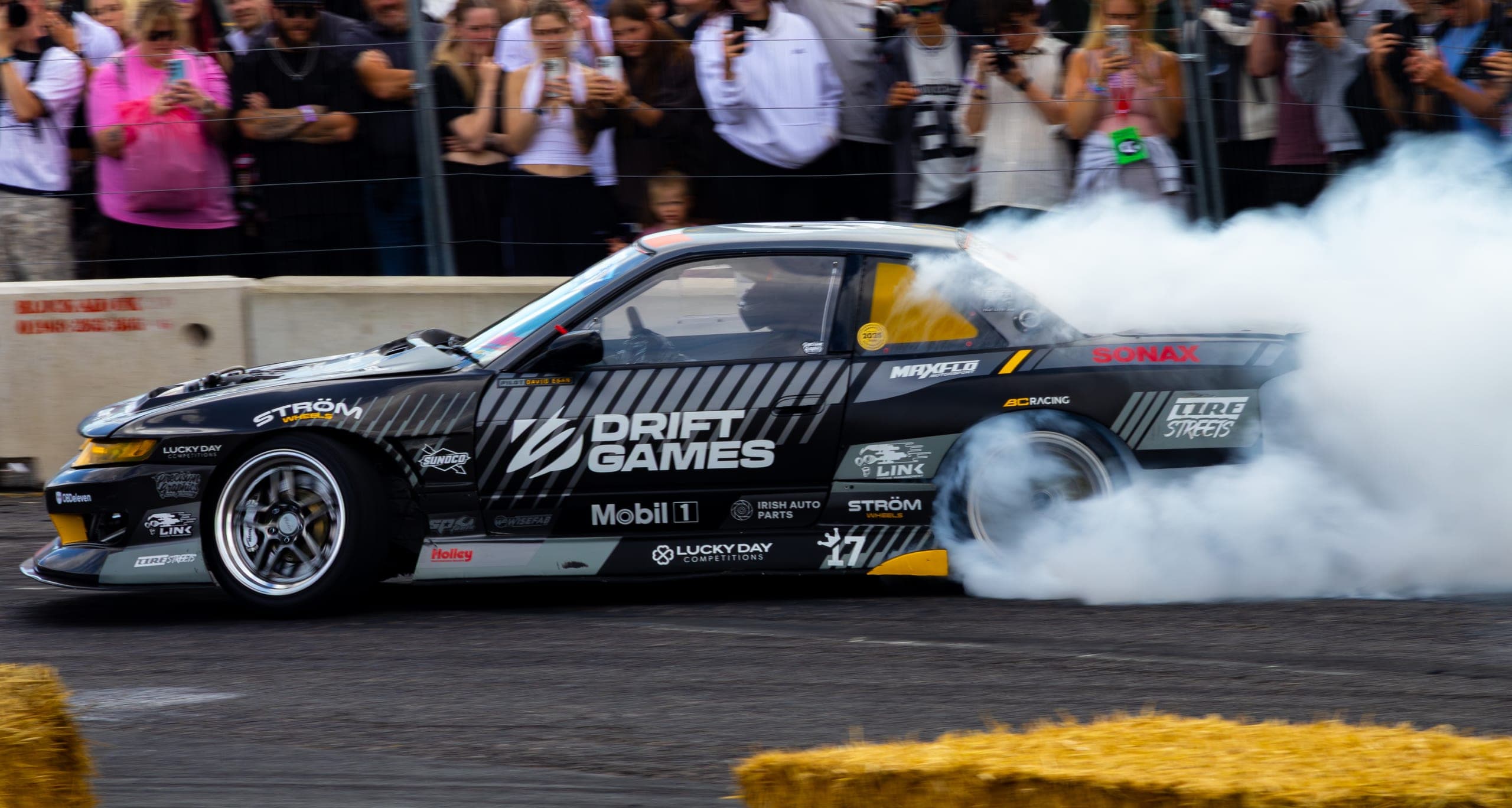 A drift car laying down heavy smoke in front of a packed crowd, Gravity 2026